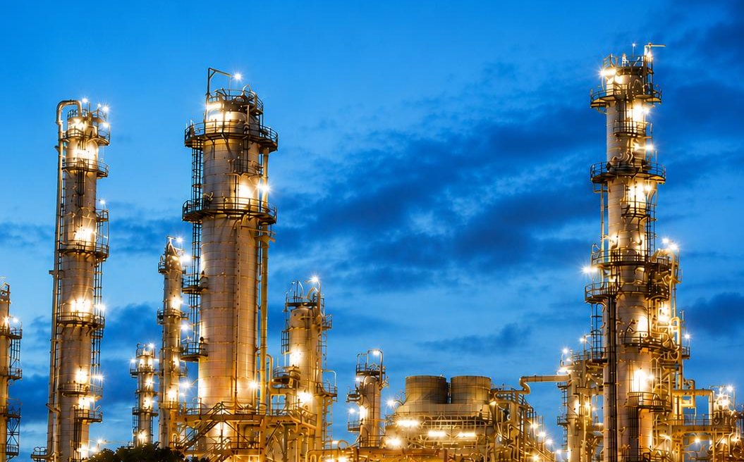 Illuminated oil refinery towers at dusk in Kuwait
